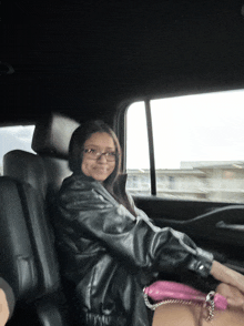 a woman wearing glasses is sitting in the back of a car