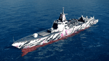 a large ship is floating in the ocean with a camouflage paint job on it