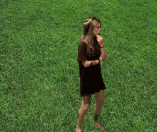 a woman in a black dress is standing in a field of grass