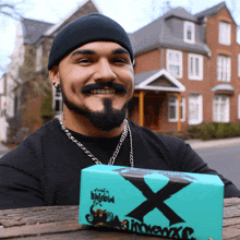 a man with a beard and mustache is holding a box that says " x " on it