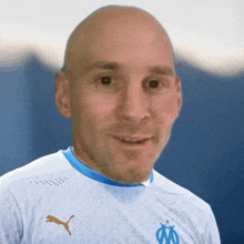 a close up of a bald man wearing a blue and white puma jersey .