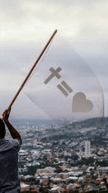 a man is holding up a flag with a cross and a heart on it .