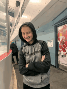 a girl wearing a champion hoodie is standing in front of a hockey poster