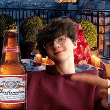 a bottle of budweiser sits next to a young boy wearing glasses