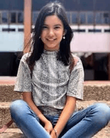 a young girl is sitting on a set of steps with her legs crossed .