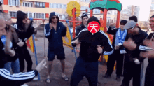 a group of people are dancing in front of a playground with a red sign that says ' 天 '