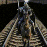 a man in a knight 's armor is riding a horse down train tracks