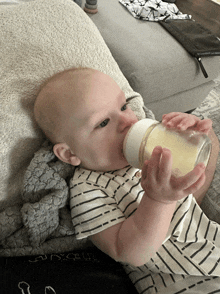 a baby is drinking milk from a bottle that says ' breastfeeding ' on the label