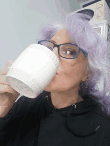 a woman with purple hair is drinking from a white cup