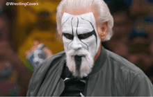 a man with white face paint and a beard is wearing a jacket