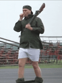 a man in a green shirt and white shorts is holding a gun