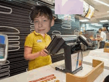 a young boy is standing behind a counter in a mcdonald 's restaurant .