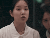 a woman in a white shirt is making a funny face while sitting next to another woman .