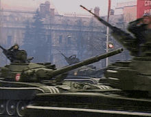 a row of military tanks are driving down a street in front of a red building that says cnn