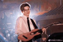 a man in a white shirt and tie is holding a guitar in front of a sign that says yo