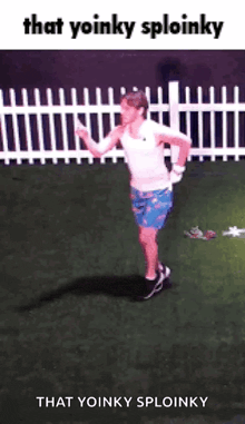 a man in a white tank top and blue shorts is running on a grassy field .