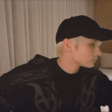 a person wearing a black hat and a black sweater is making a stop sign