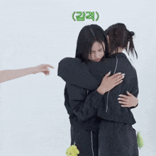 a woman is pointing at another woman while they hug each other .