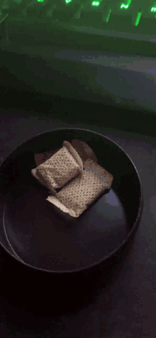 a black bowl with a few pieces of bread in it