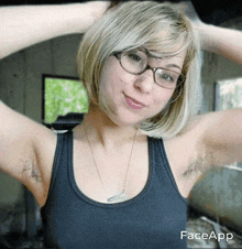 a woman wearing glasses and a black tank top has her hairy armpits showing