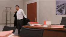 a man in a white shirt and tie is standing in front of a stack of books on a desk