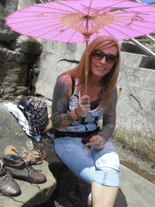 a woman sitting under a pink umbrella with a hat that says " i love you " on it