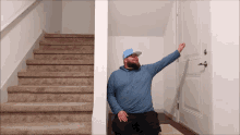 a man in a blue hoodie is sitting on the floor in front of a set of stairs