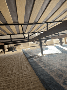 the underside of a bed frame with a blue rug on the floor