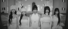 a black and white photo of a group of women standing in front of a building .