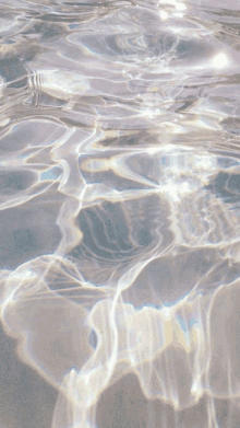 a close up of a body of water with a rainbow reflection