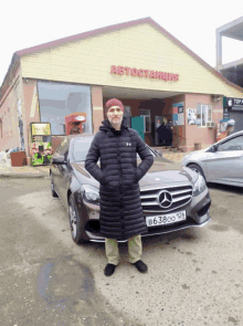 a man stands in front of a mercedes with a license plate that says b638oo 128