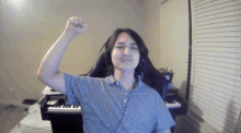 a man in a striped shirt is flexing his muscles in front of a piano