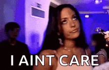 a woman is standing in a room with the words `` i ain t care '' written on the screen .