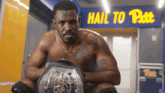 a man holding a wrestling belt in front of a sign that says " hail to pitt "