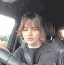 a woman is sitting in the driver 's seat of a car with her eyes closed .