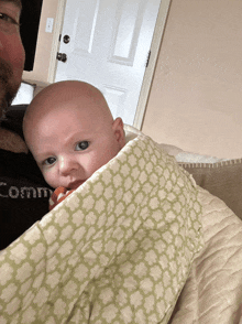 a baby is being held by a man wearing a shirt that says comme