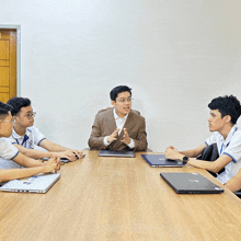 a group of young men sitting around a table with laptops