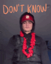 a man wearing a red hat and a lei with the words " don 't care " behind him
