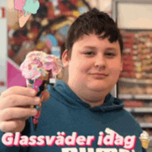 a boy in a blue shirt is holding an ice cream cone with sprinkles on it .