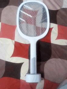 a white mosquito swatter is sitting on a bedspread