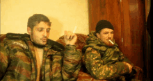 two men sitting on a couch one of whom is wearing a jacket with a patch that says cccp on it