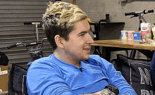 a man wearing a blue shirt is sitting in front of a table with a container of ice cream on it