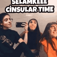 three girls are taking a selfie in front of a mirror with a cell phone .