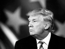 a man in a suit and tie is standing in front of a flag