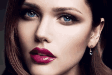 a close up of a woman 's face with blue eyes and red lipstick .