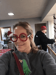 a woman wearing a santa hat and glasses is smiling for the camera