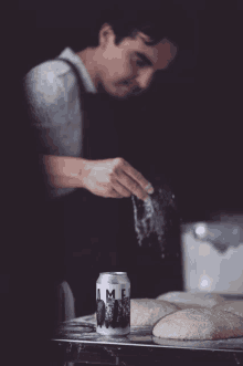 a can of lime beer sits on a table next to a man sprinkling flour