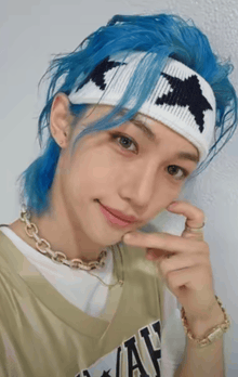 a young man with blue hair is wearing a headband with a star on it and a necklace