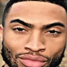 a man with a beard and pink lips is looking at the camera .