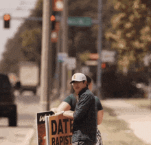 a man is holding a sign that says " date rapist "